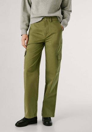 Persona che indossa pantaloni cargo verde oliva con tasche a patta e scarpe nere, abbinati a una felpa grigia chiara.