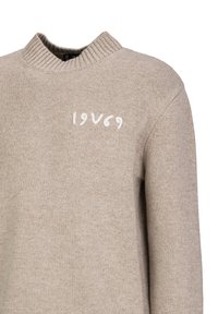 Beige gestrickter Pullover mit hohem Rippkragen und gestickter "1969"-Aufschrift in Weiß auf der Vorderseite. Weiche Textur und lässige Passform.