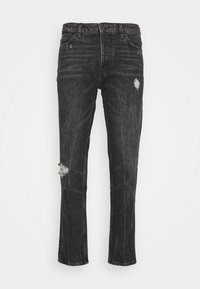 Jeans negros de corte slim con detalles desgastados en el muslo y la rodilla, estilo clásico de cinco bolsillos y cierre de botón en la cintura.