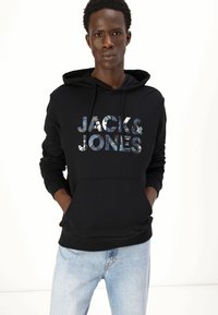 Felpa nera con cappuccio e tasca frontale; presenta il logo "JACK & JONES" in un motivo colorato; polsini e orlo a coste, texture morbida.