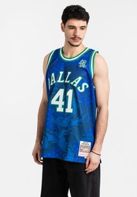 Camiseta de baloncesto en azul con acentos verdes. Presenta "DALLAS" y "41" en una fuente grande. Patrón detallado de dragón y etiqueta del logo de la NBA en el dobladillo.