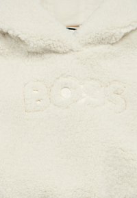 Κρεμ φλις φούτερ με κεντημένο λογότυπο "BOSS". Διαθέτει κουκούλα και απαλό, υφασμάτινο υλικό με υφή για ζεστασιά.