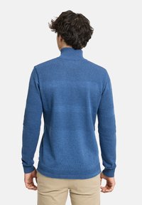 Blauer Pullover mit hohem Kragen, ausgestattet mit einer strukturierten Oberfläche und kontrastierenden horizontalen Streifen. Weiches Strickmaterial, lange Ärmel.