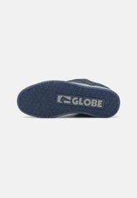 Sole plave skates cipela s teksturiranim gripom, s istaknutim sivim "GLOBE" logom i obrascem gume za prijanjanje.
