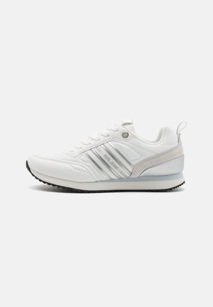 White athletic shoe with a smooth leather upper, reflective silver accents, three white stripes, and a textured rubber sole.