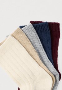 Πλεκτές κάλτσες σε τέσσερα χρώματα: εκρού, μπεζ, γκρι, ναυτικό μπλε και μπορντό. Καθένα έχει ριμπ υφή και διαφορετικά μήκη υφάσματος.