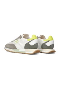 Baskets blanches avec des accents gris et vert lime, présentant une texture pailletée, une semelle rembourrée et un détail de logo distinct sur le côté.