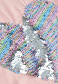 Paillettenstof in pastelkleuren (blauw, groen, roze, zilver) gerangschikt in een golfpatroon op een zachte roze achtergrond, met een glanzende, gestructureerde oppervlakte.