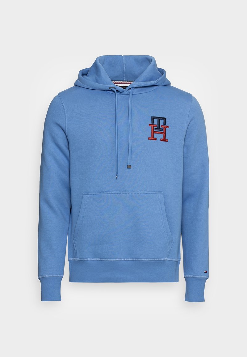 Sudadera con capucha azul claro hecha de tela suave, con bolsillo frontal, capucha con cordón, y logo bordado en azul oscuro y rojo.