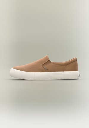 Καφέ αθλητικό παπούτσι τύπου slip-on με λευκή λάστιχη σόλα, ελαστικά πλαϊνά πάνελ και μικρή ετικέτα της μάρκας στο πλάι.
