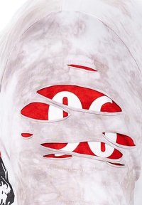 T-shirt bianco sfilacciato con grande grafica rossa, diverse sezioni a taglio che rivelano il sottostrato, texture morbida e scollo rotondo.