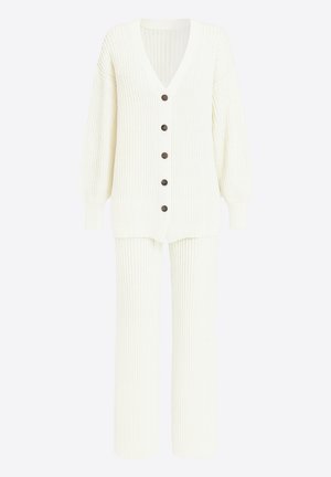 Kremowy sweter na guziki z dekoltem w serek, długimi rękawami i sześcioma brązowymi guzikami; w komplecie z pasującymi szerokimi spodniami z prążkowanej dzianiny.