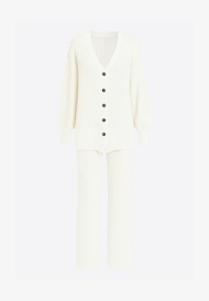 Kremowy sweter na guziki z dekoltem w serek, długimi rękawami i sześcioma brązowymi guzikami; w komplecie z pasującymi szerokimi spodniami z prążkowanej dzianiny.