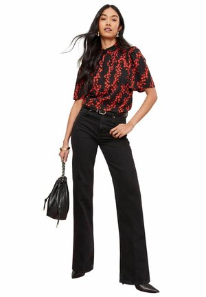 Blouse à motifs floraux rouges à manches courtes, portée avec un jean noir taille haute et un sac à main noir. Pantalons longs à jambes larges.