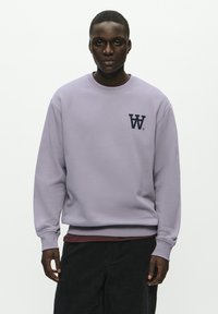 Lavender sweatshirt in a soft material, featuring a crew neck, ribbed cuffs, and a dark navy logo on the left chest.