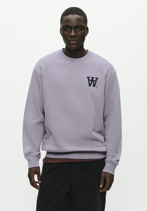 Lavender sweatshirt in a soft material, featuring a crew neck, ribbed cuffs, and a dark navy logo on the left chest.