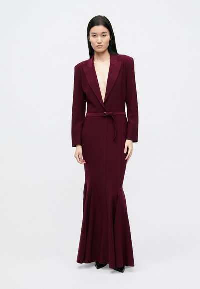 Burgunderfarbenes Abendkleid mit tiefem Ausschnitt, langen Ärmeln, tailliertem Schnitt und ausgestelltem Saum. Hergestellt aus glattem Stoff, mit Gürtel versehen.