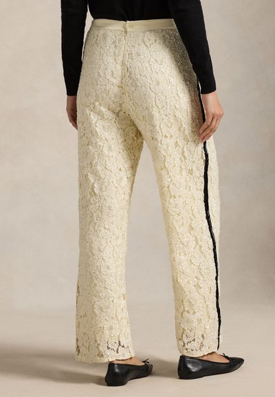 Krämfärgade spetsbyxor med blommönster, med en svart sidrand och knappstängning baktill. Texturerade och figursydda.