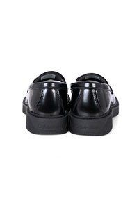 Le scarpe nere in vernice presentano una punta arrotondata, una superficie liscia e una suola in gomma texturizzata, con il marchio 'Calvin Klein' sul retro.