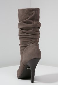 Stivali alti fino al ginocchio in suede grigio morbido, con punta affilata e tacco sottile, caratterizzati da una texture arricciata lungo il gambale.