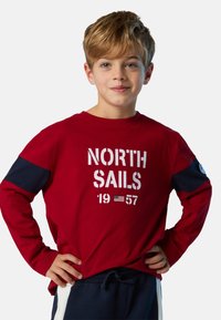 Rotes langärmliges T-Shirt mit marineblauen Akzenten, bedruckt mit "NORTH SAILS 1957" in Weiß. Weicher Stoff, lässige Passform, Rundhalsausschnitt.