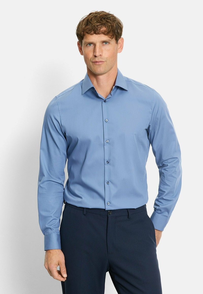 Light blue button-up shirt with long sleeves, a classic collar, and subtle texture, paired with dark navy trousers.