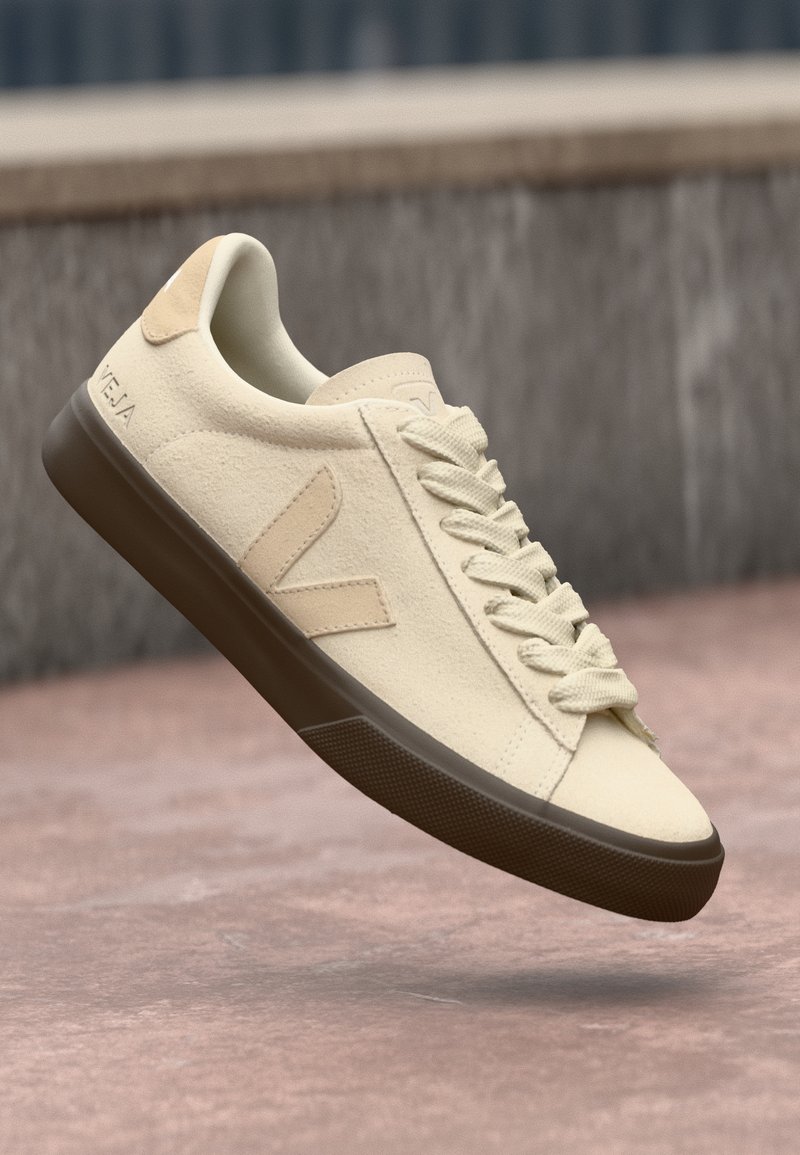 Sneaker in ecopelle beige con lacci crema, suola in gomma marrone e dettaglio del logo sul tallone. Design pulito con accenti tonali sottili.
