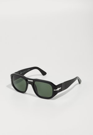 Schwarze Sonnenbrille mit quadratischem Rahmen, grünen Gläsern, silbernen Akzenten an den Bügeln und mattem Finish. Verfügt über ein schlankes, modernes Design.