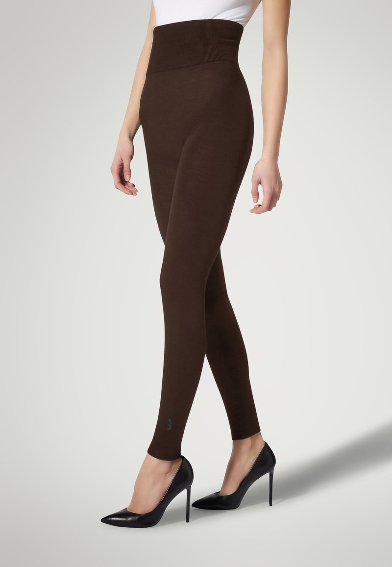 Leggings marroni con vita alta, realizzati in materiale morbido, design aderente, texture liscia, abbinati a tacchi alti neri.