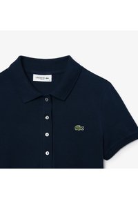 Mörkblå polo-shirt i bomull, med klassisk krage, tre knappar framtill och en broderad grön krokodil-logotyp på bröstet.