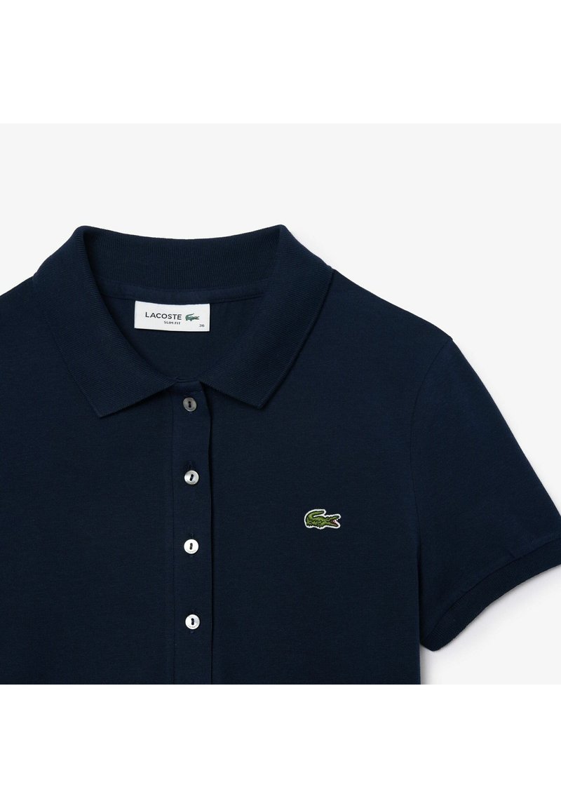 Marineblauwe polo gemaakt van katoen, met een klassieke kraag, een sluiting met drie knopen en een geborduurd groen krokodillenlogo op de borst.