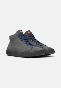Zapatillas altas grises con cordones azules, con una parte superior de tela texturizada y una suela de goma negra, etiquetadas "Camper" en la lengüeta.
