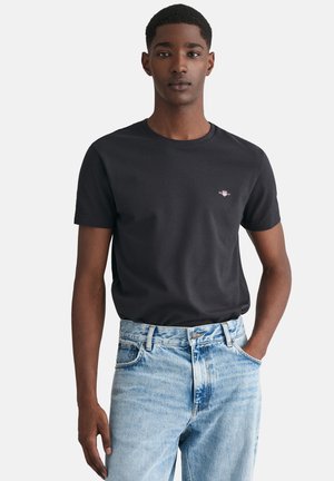 Zwarte katoenen t-shirt met een ronde hals en korte mouwen, gecombineerd met lichtblauwe denim jeans met een vervaagde wassing.