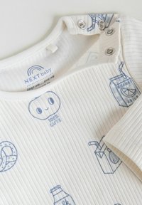 Hvid ribbet babybody med blå illustrationer af snacks og drikke, inklusive pretzel, juiceæsker og et smilende ansigt markeret med "100 % sød".