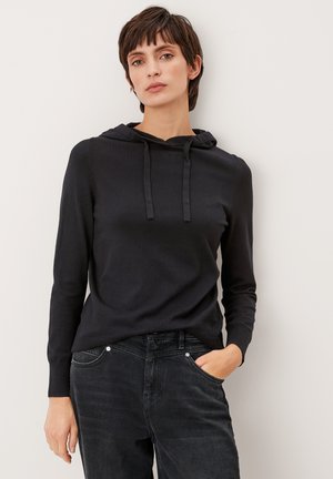 Czarna bluza z kapturem, wykonana z miękkiego materiału, z regulowanym sznurkiem, prążkowanymi mankietami i dołem, w połączeniu z ciemnymi dżinsami. Prosty, dopasowany krój.