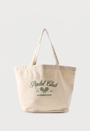 Borsa tote in tela beige con testo verde "Padel Club International" e grafica di racchette da padel incrociate sul davanti.