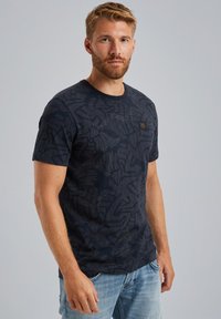 Camiseta de manga corta azul marino con un patrón texturizado. Presenta un cuello redondo y una pequeña etiqueta de la marca en la parte frontal izquierda.