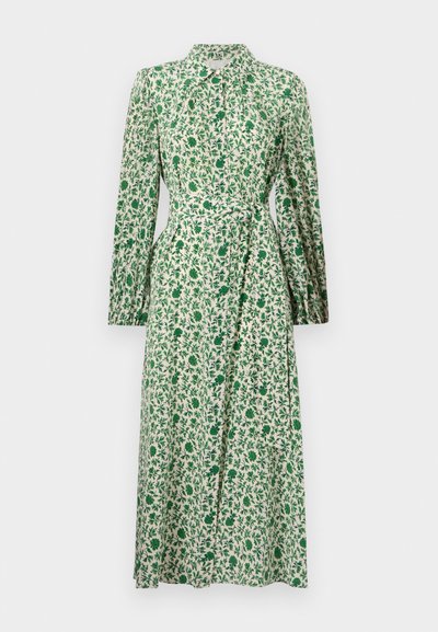 Ilga rankovė suknelė iš šviesios medžiagos, puošta žaliais ir baltais gėlių raštais, su mygtukų užsegimu priekyje ir įlankstytu juosmeniu, suteikiančiu formą.