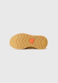 Suela de zapato en goma de color tostado claro con un patrón de banda de rodadura en zigzag. Logo naranja centrado con un diseño de montaña. Forma plana, superficie texturizada.