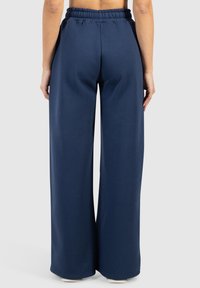 Navyblaue weite Sweatpants mit elastischem Bund und glatter Textur; keine sichtbaren Beschläge oder Muster.