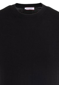 Pull noir col rond avec une étiquette indiquant "FELIX HARDY" et la taille "M" cousue à l'intérieur du col.