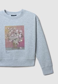 Felpa grigia con una stampa floreale di un vaso con rose rosa, accompagnata da un testo che descrive l'opera d'arte di Van Gogh.