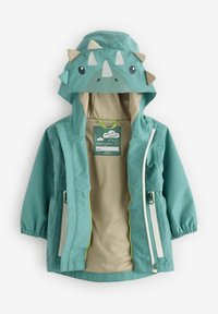 Veste imperméable teal avec une capuche de dinosaure, présentant des piquants, une doublure en mesh beige et des accents de fermetures éclair blanches sur les poches et à l'avant.
