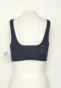 Navy blue sports bra with wide straps, elastic ribbed band, and small white text on the back, displayed on a white mannequin torso.