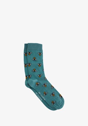 Türkisblaue Socken mit einem ganzflächigen Bienenmuster in Schwarz und Gelb. Hergestellt aus weichem Material, mit einem gerippten Bündchen und einer glatten Textur.