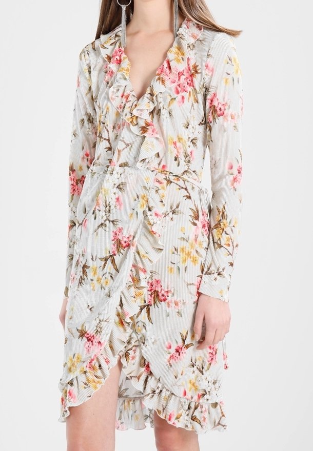 Femme portant une robe portefeuille à manches longues à imprimé floral, avec volant et col en V.