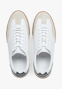 Białe skórzane sneakersy z zamszowymi akcentami i perforowanymi detalami. Gumowa podeszwa i wzmocniony czubek, z kontrastującym ciemnym piętkiem.