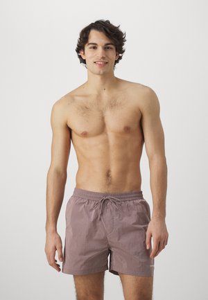 Bañadores de hombre en un suave color malva, con cintura elástica y cordón, fabricados en tejido ligero y con un diseño sencillo.