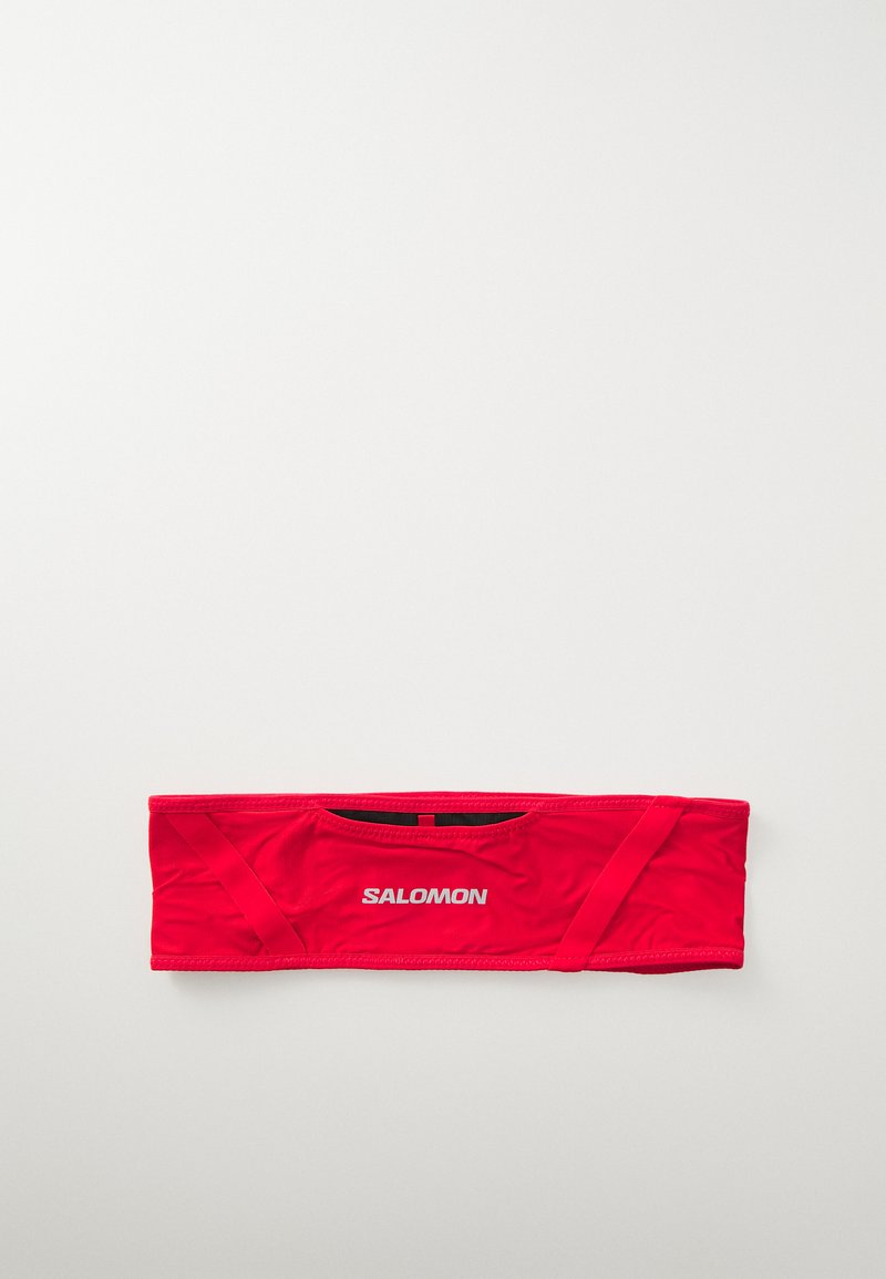 Red athletic headband made of stretchy fabric with a smooth texture. Features a small logo and elastic edges for a secure fit.