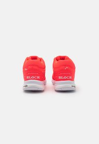 Neon rosa sportsko med hvite detaljer, et nettingoverdel for ventilasjon og teksturerte såler. Har "BLOCK"-merke på hælen.